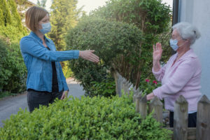 Senior-woman-with-mask-greeting-neighbor